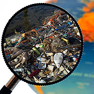 Nondegradable rubbish / refuse in water washed ashore seen through magnifying glass held against illuminated terrestrial globe